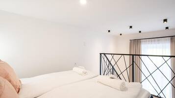 A hotel room with two beds, a window with curtains, and a ceiling light.