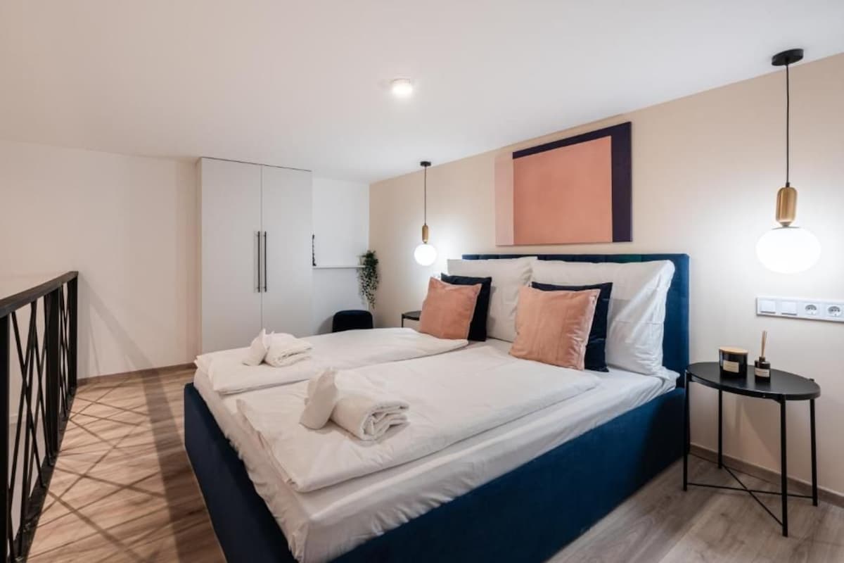 Una habitación de hotel con cama, mesita de noche y lámpara de pared.