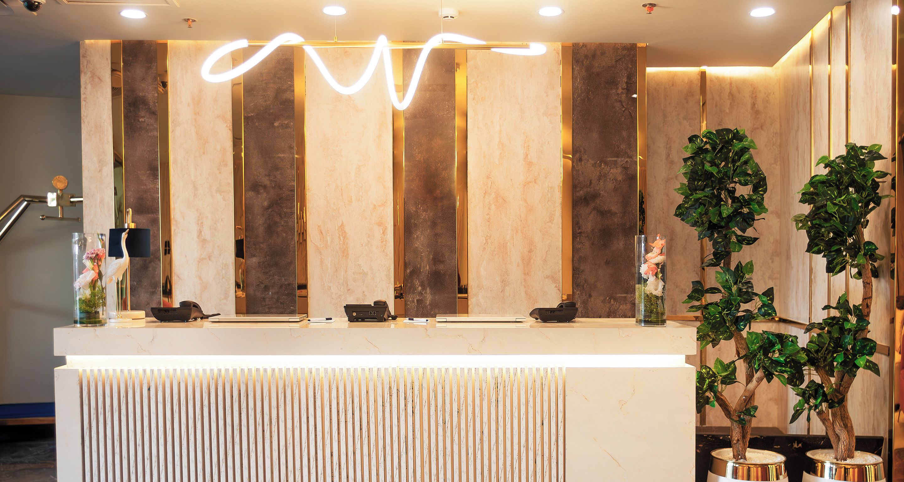 Un mostrador de recepción de diseño moderno, con paneles de madera verticales y una encimera de mármol.