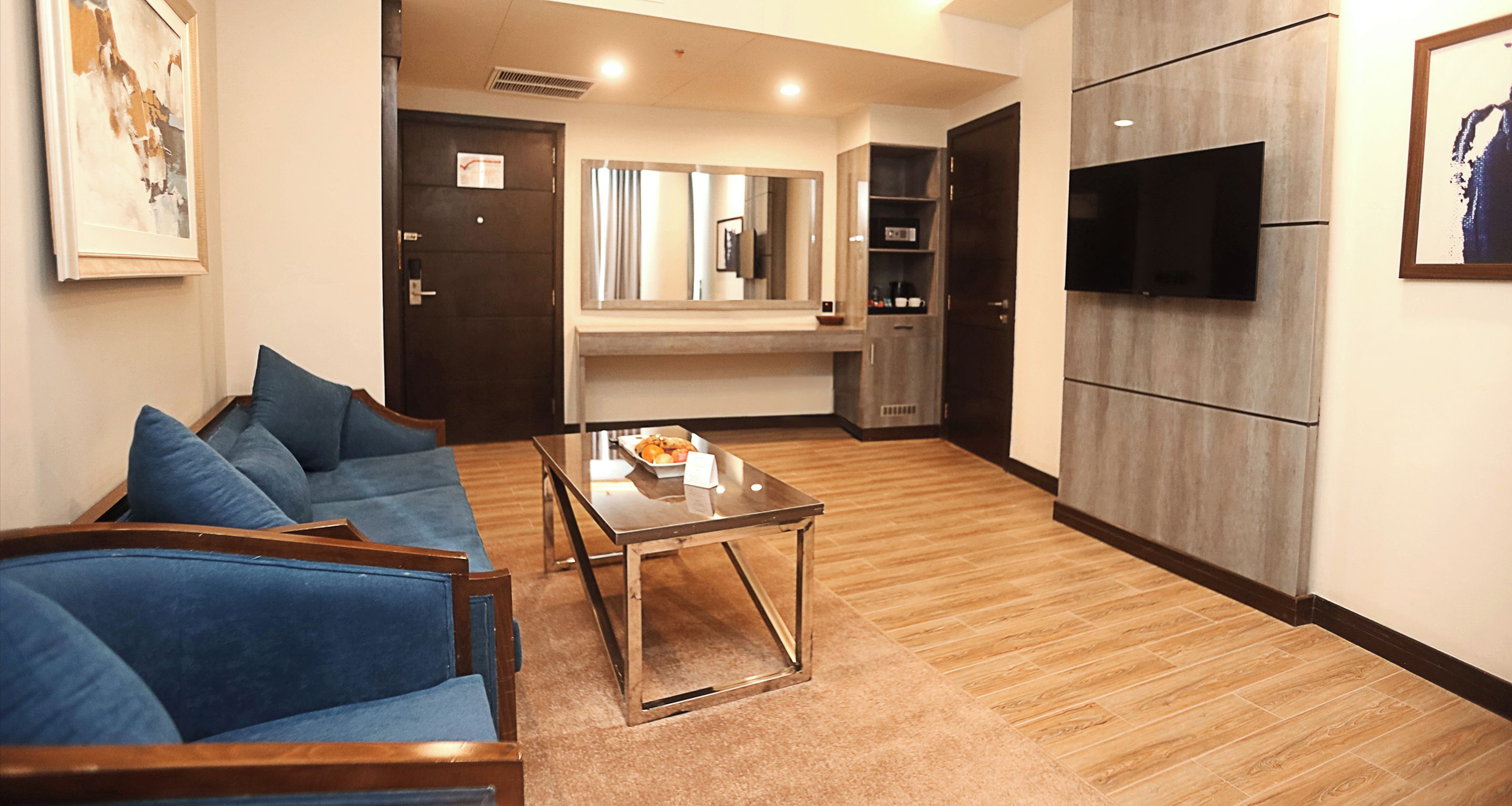 A modern living room with a sofa, coffee table, and a flat-screen TV mounted on the wall.