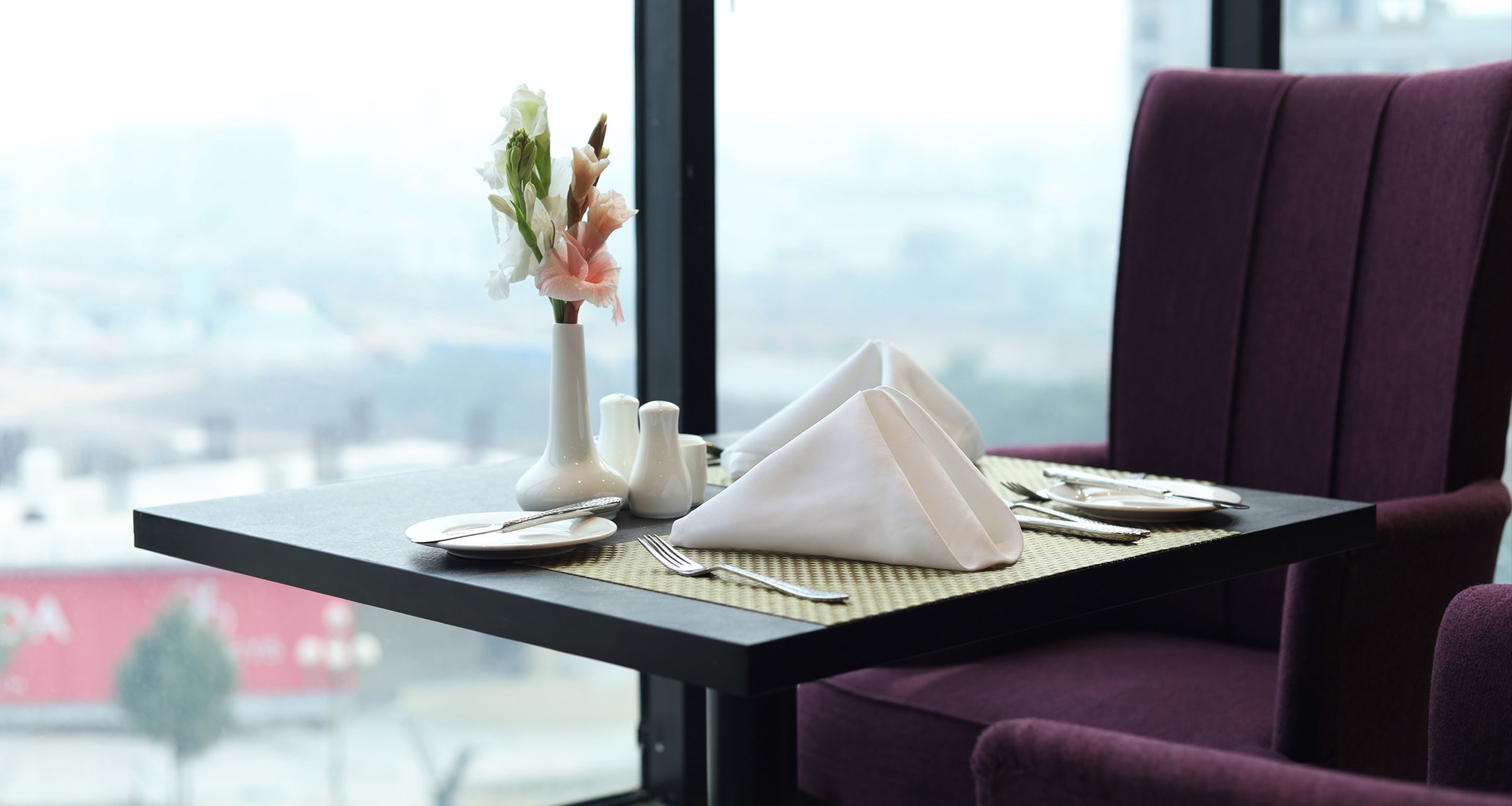 Una mesa de comedor bien dispuesta con un florero, saleros y pimenteros, y servilletas dobladas.