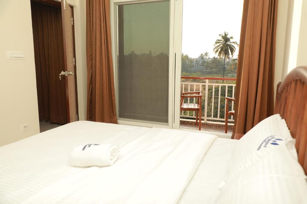 Habitació d'hotel amb un llit, una porta corredissa de vidre a un balcó i una cadira al balcó.