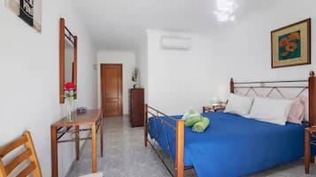 Une chambre à coucher avec un lit, un bureau, une chaise, une armoire et une porte.