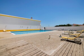 Ein Poolbereich auf dem Dach mit klarem, blauem Pool, Liegestühlen und einer Holzterrasse.