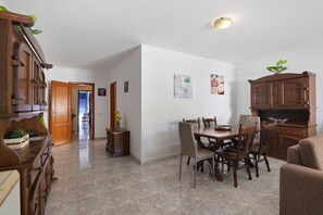 A dining area with a wooden table and chairs, a cabinet, and a plant on the wall.