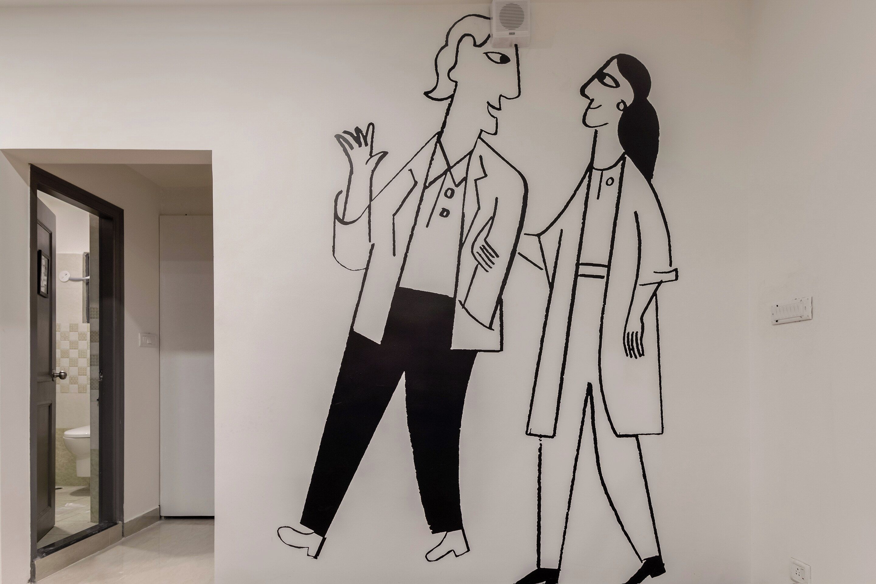 Un pasillo con una pared blanca que presenta un dibujo en blanco y negro de dos personas caminando.