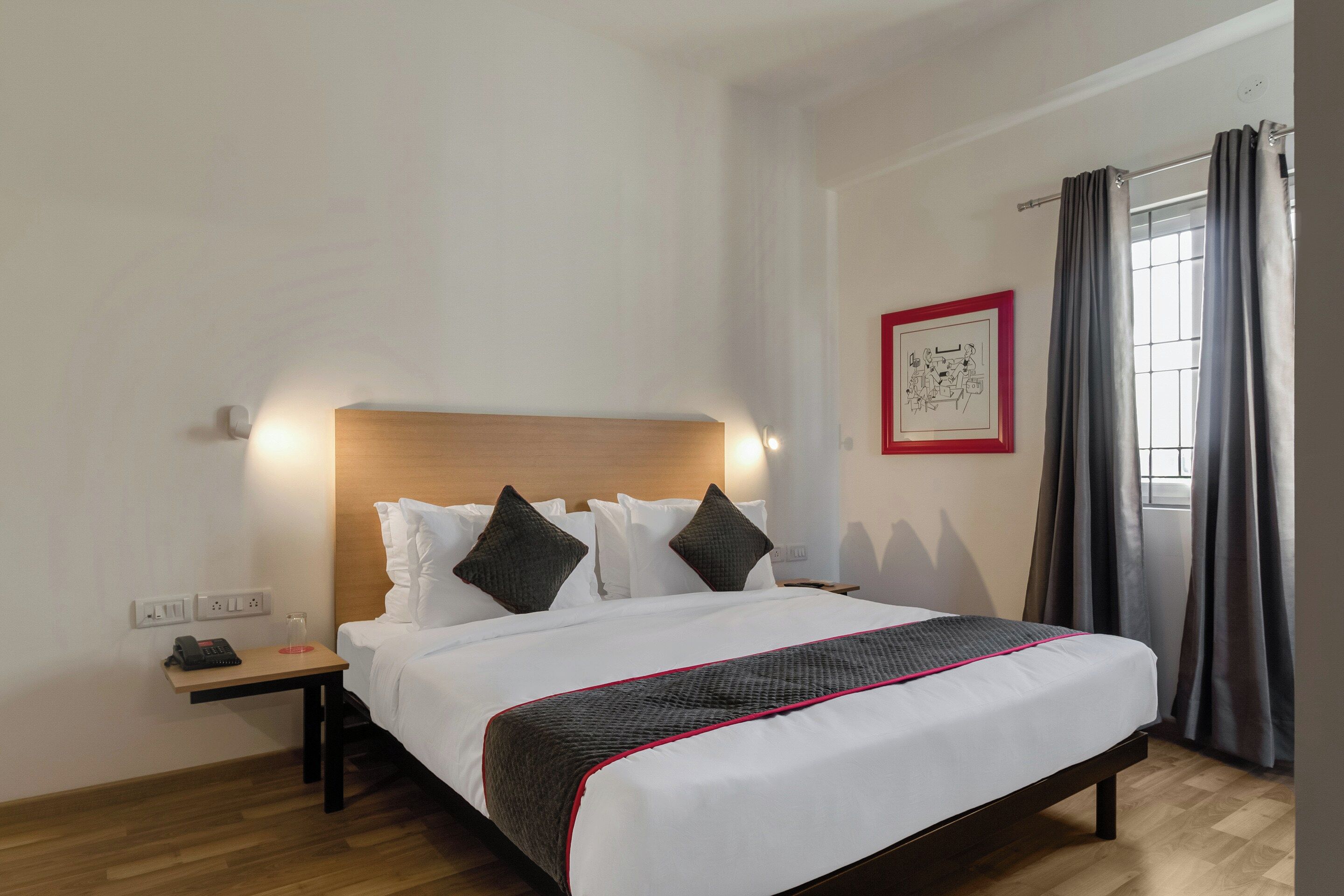 Una habitación de hotel con cama, mesita de noche y un cuadro en la pared.