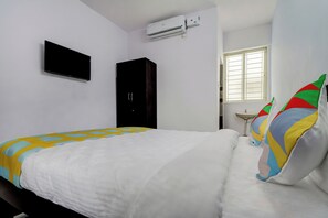 Un dormitorio con cama, televisor de pantalla plana, aire acondicionado, armario y ventana con persianas.