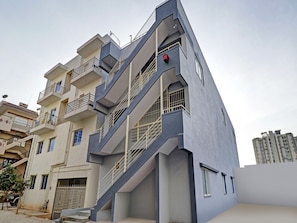 Un edifici residencial de diverses plantes amb balcons, entrada tancada i escala que condueix als pisos superiors.