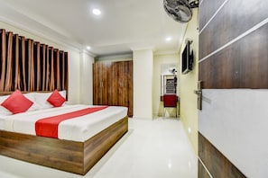 A hotel room with a bed, a wardrobe, a mirror, and a fan. - Hotel O Ommiyo Stay. (Bangalore)