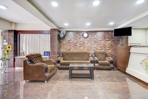 A hotel lobby with a reception desk, a sofa set, a coffee table, and a wall-mounted clock. - Hotel O Ommiyo Stay. (Bangalore)