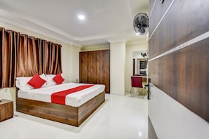 A hotel room with a wooden bed, red pillows, a bedside table, a mirror, and a wardrobe. - Hotel O Ommiyo Stay. (Bangalore)