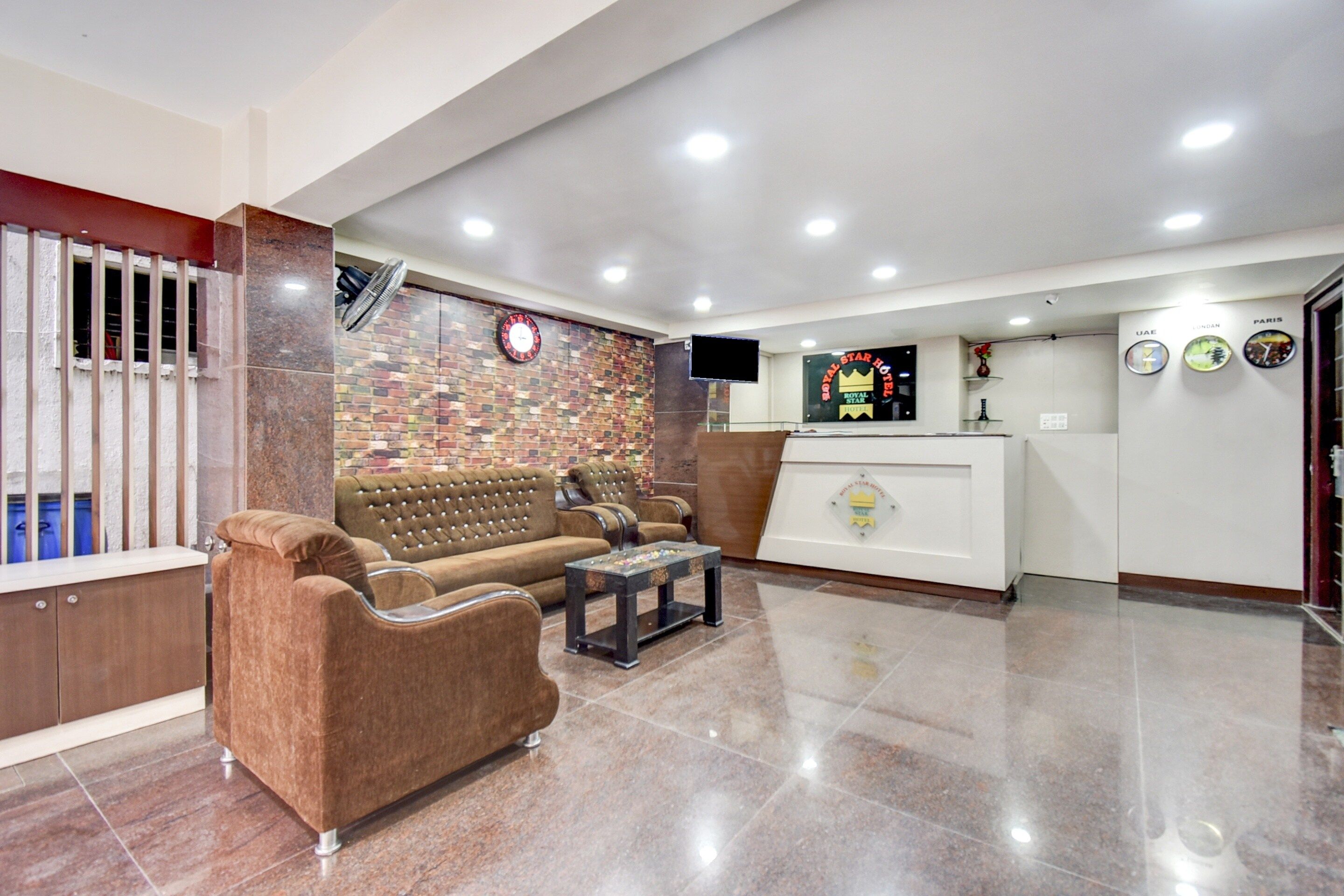 Un vestíbulo de hotel con mostrador de recepción, zona de estar y un reloj en la pared.