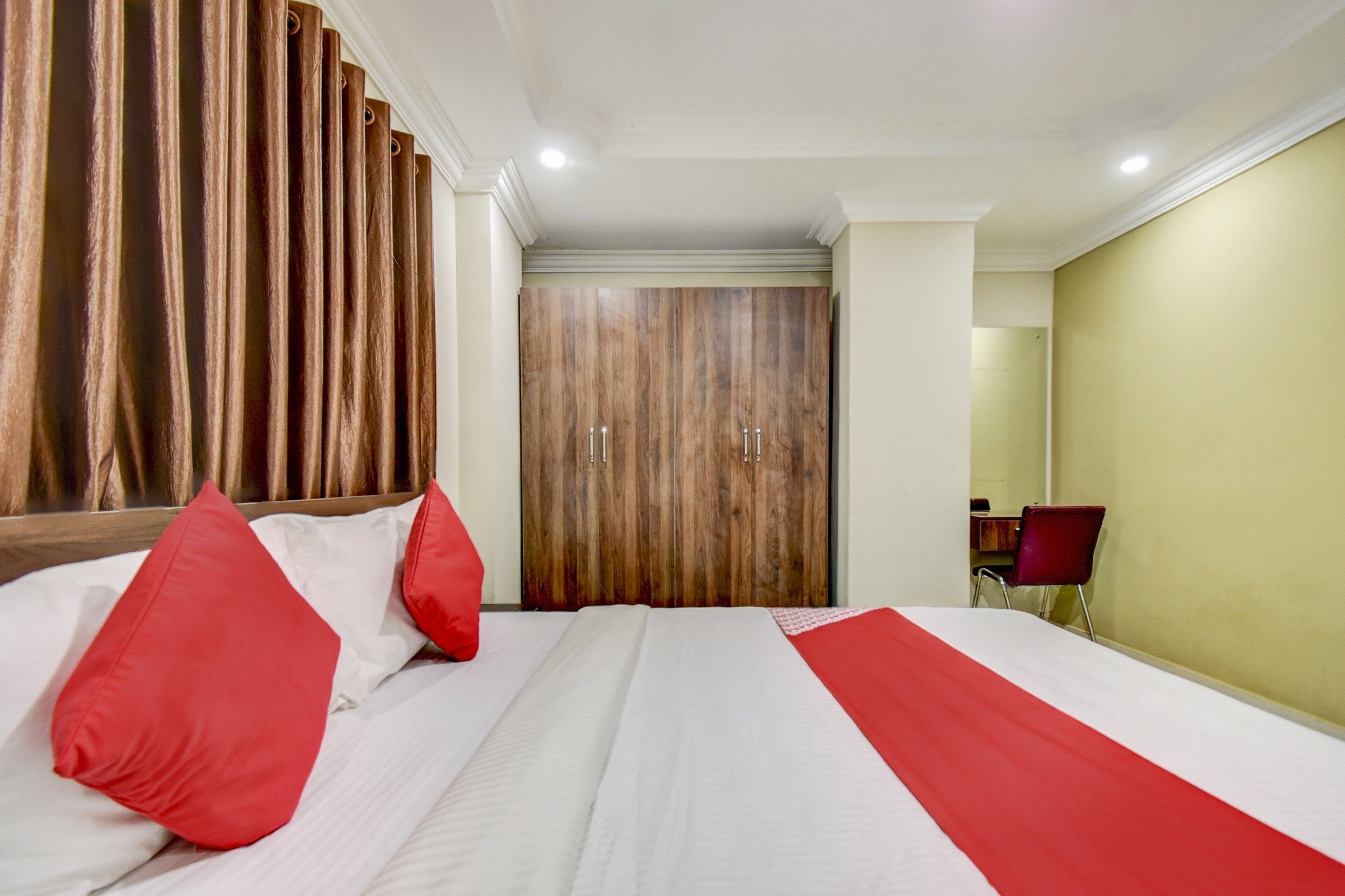 Habitación de hotel con una cama grande, un armario de madera y un escritorio con silla.