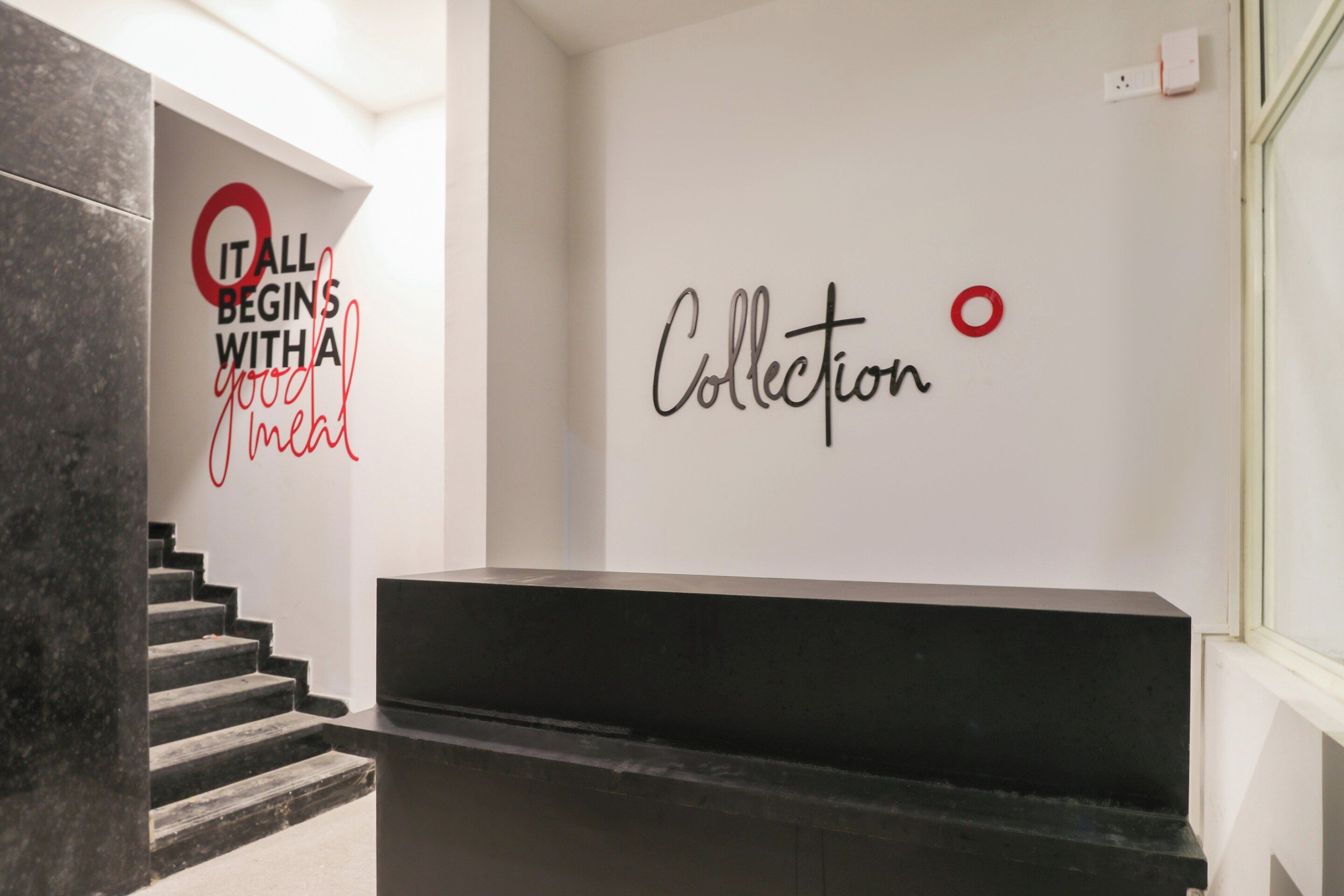 Una escalera conduce a un área de recepción con un letrero en la pared que dice 'IT ALL BEGINS WITH A good meal' y otro letrero que dice 'Collection'.