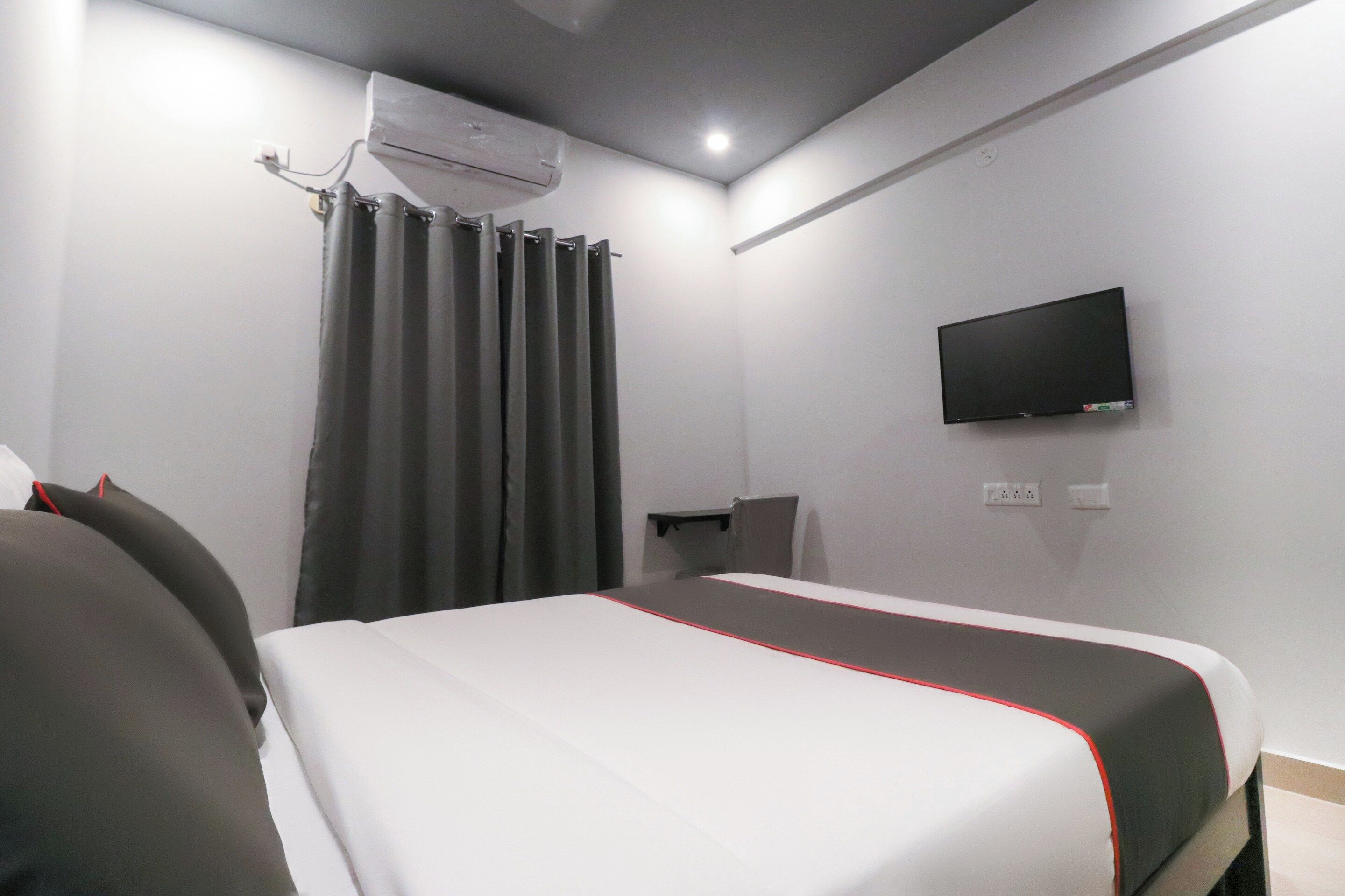 Habitación de hotel con cama, televisor de pantalla plana en la pared y aire acondicionado.