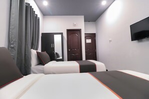 Habitación de hotel con dos camas, un televisor de pantalla plana montado en la pared y una puerta con un calendario.