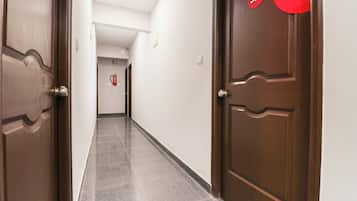 Un pasillo con dos puertas de madera, una con el número 307, que conduce a una habitación con un extintor en la pared.