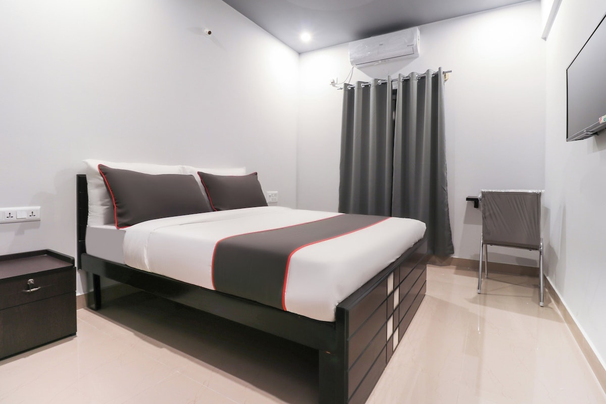Un dormitorio moderno con una cama, una silla, un equipo de aire acondicionado y un televisor en la pared.