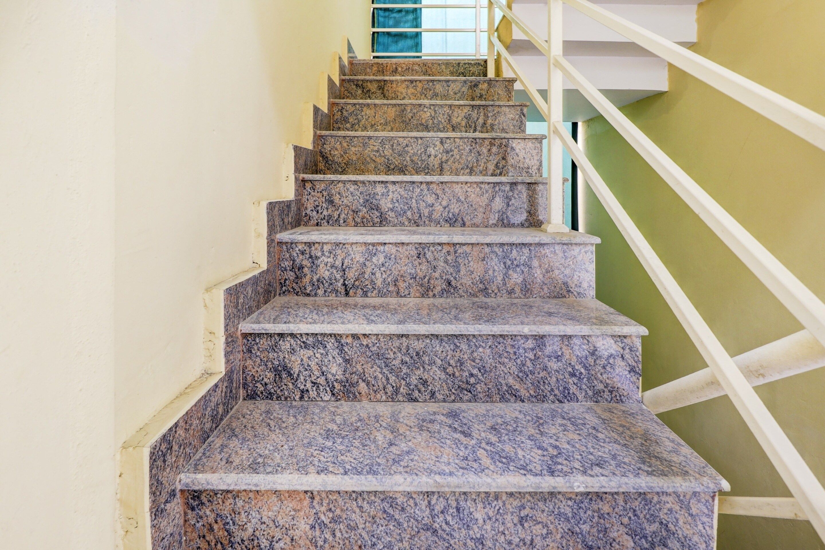 Una escalera con escalones de granito y barandillas blancas.