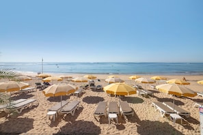 Una platja amb files de gandules i ombrelles grogues.