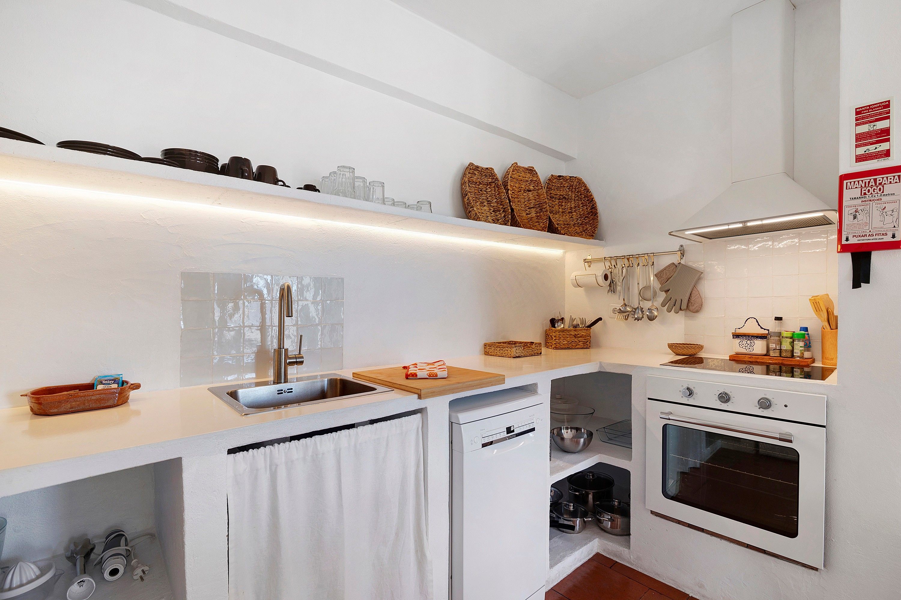 A compact kitchen with a sink, stove, and a small dish rack.
