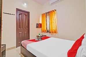A hotel room with a bed, a bedside table with a kettle, a small plant, and a window with curtains. - Hotel O Mn Residency Near Ragigudda Sri (Bangalore)