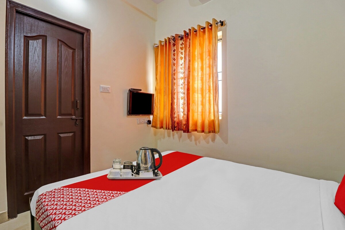 Quarto de hotel com uma cama, cafeteira e televisão na parede.