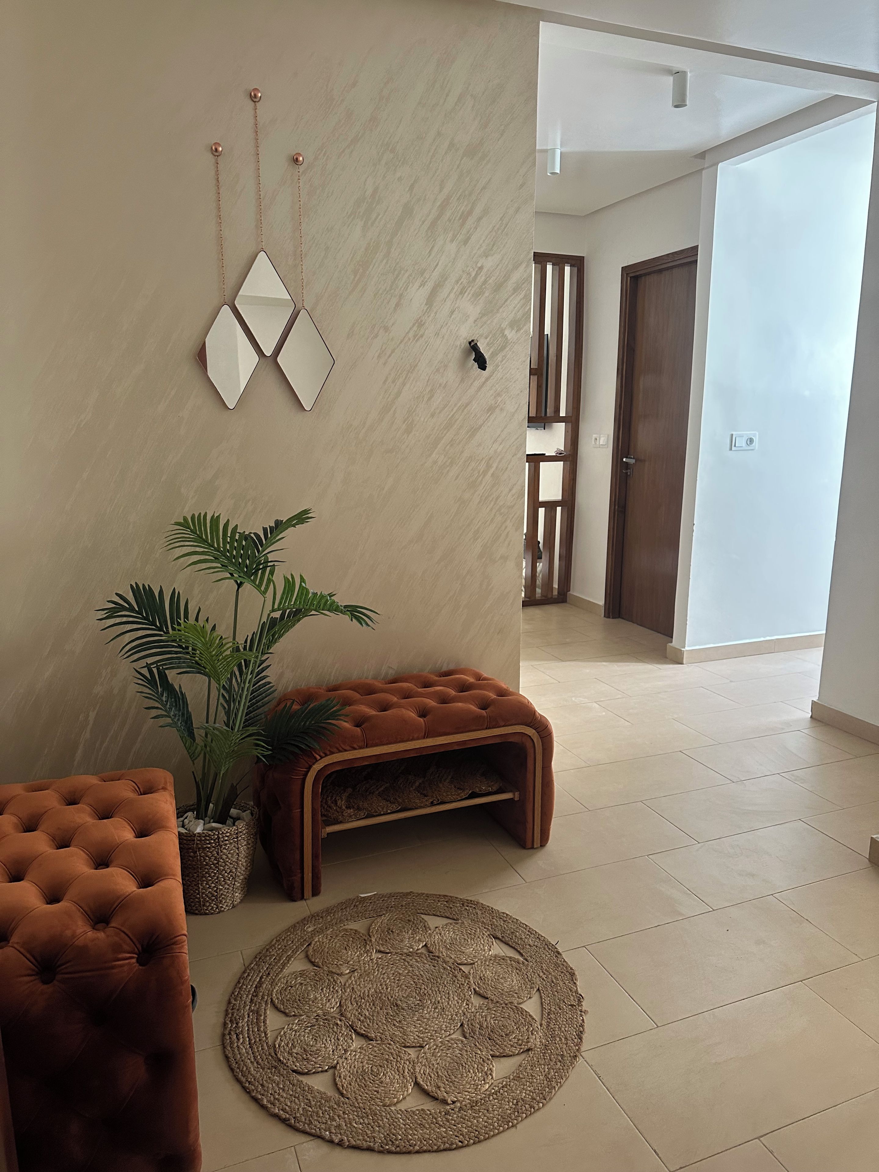 Un salon moderne avec un canapé capitonné, un tapis tissé et une plante en pot.