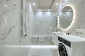 Un baño moderno con lavadora integrada, un espejo grande y zona de ducha.