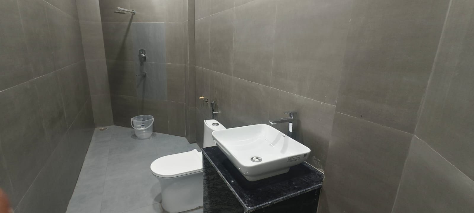 A small, modern bathroom with a toilet, a sink, and a shower.