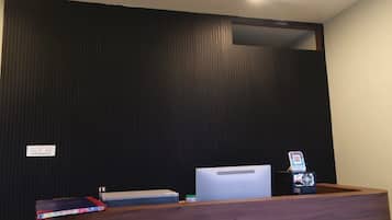 A reception desk with a computer, a QR code scanner, and a small plant.