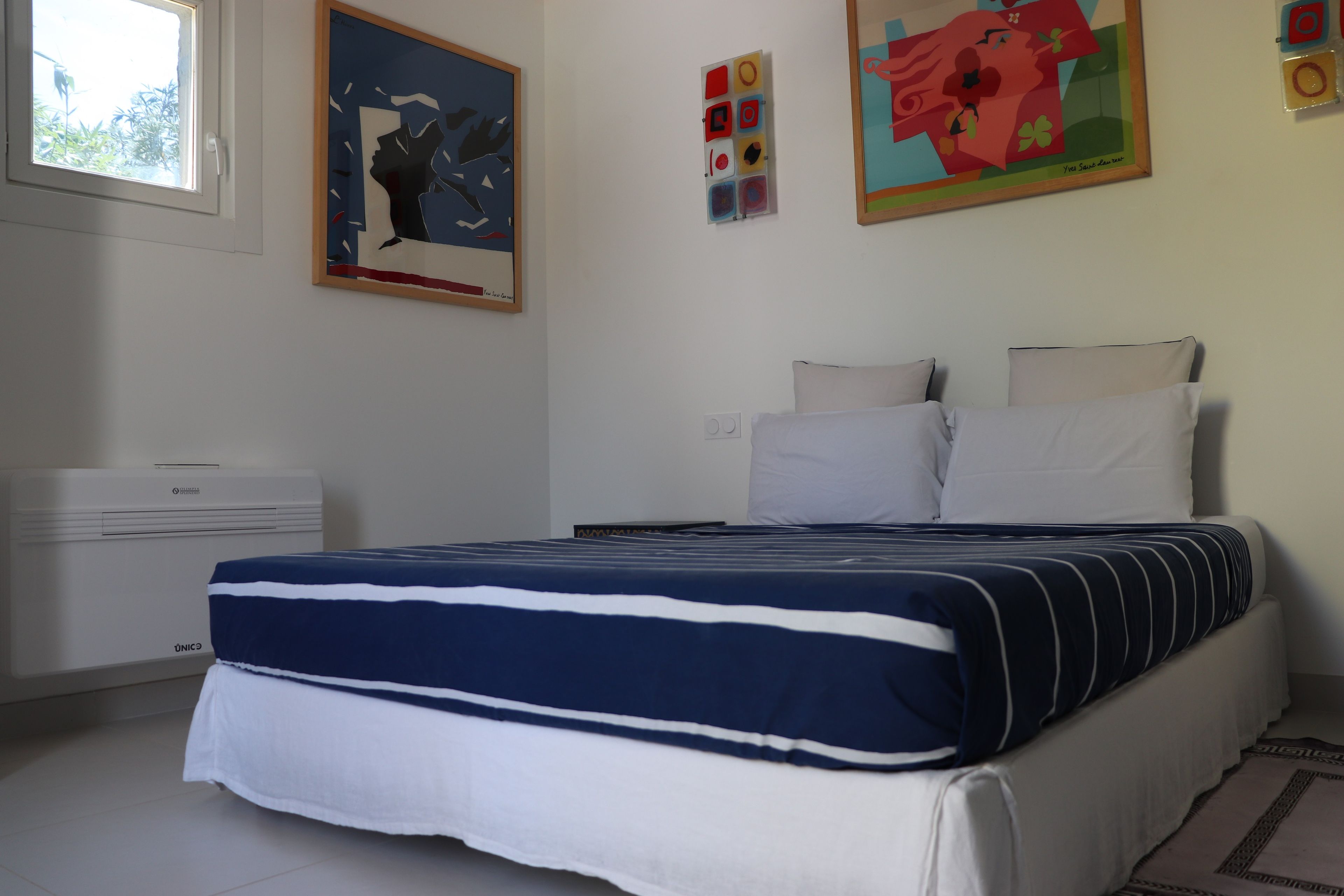 Una camera da letto con un letto, cuscini, un comodino e una finestra.