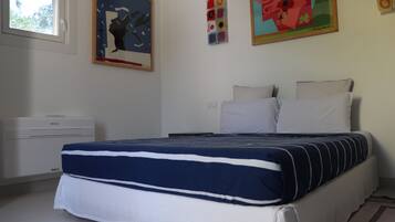 Una camera da letto con un letto, cuscini, un comodino e una finestra.
