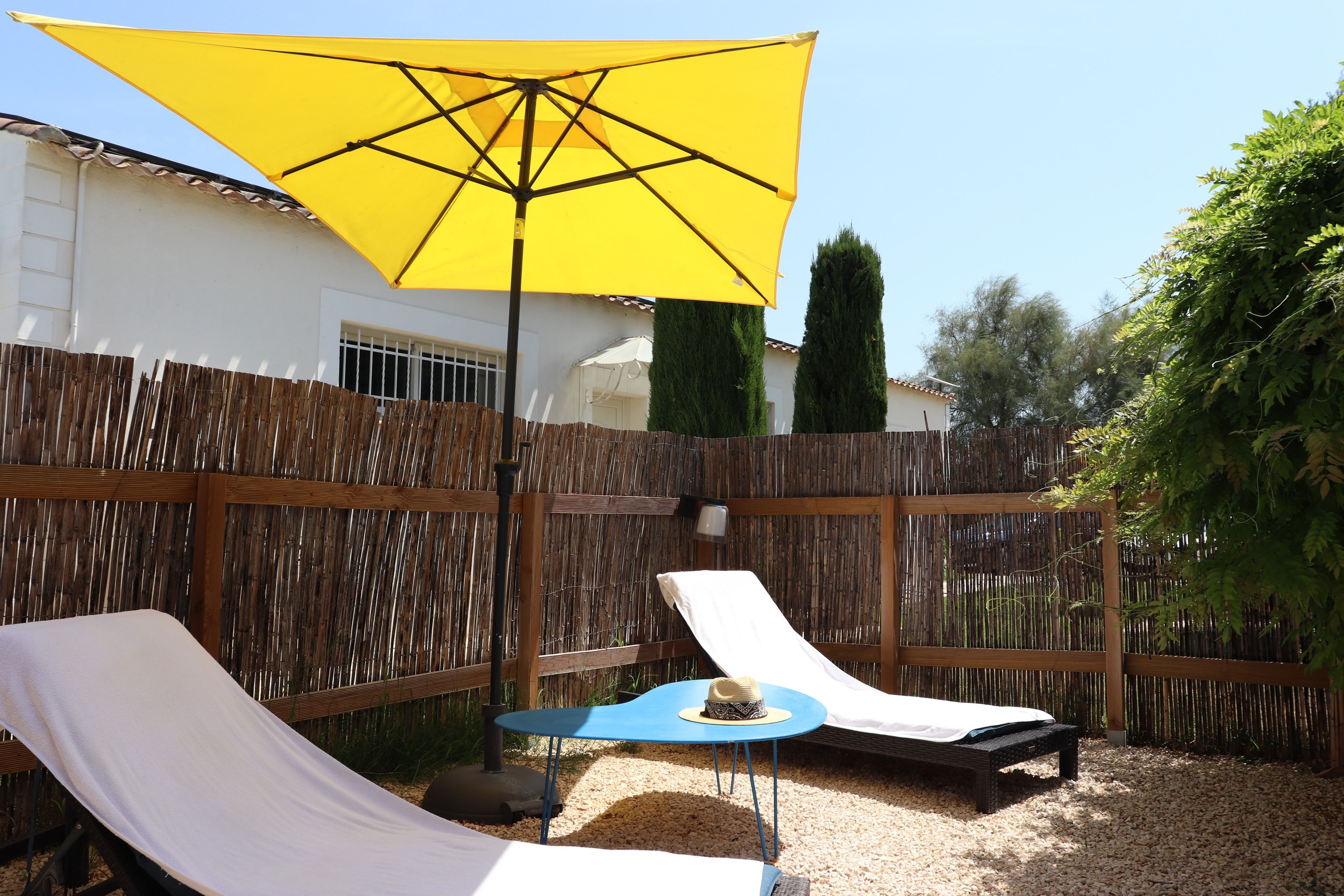 Un patio con due poltrone, un ombrellone giallo e un tavolino.