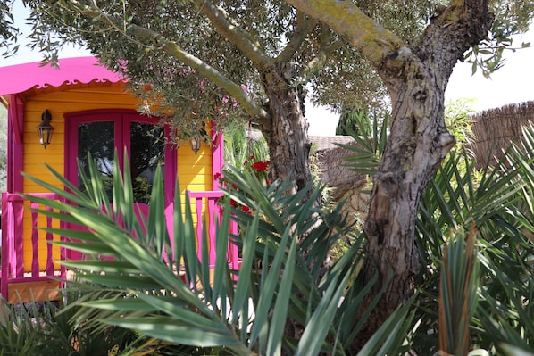 Un edificio colorato con facciata rosa e gialla, immerso nel verde e alberato.