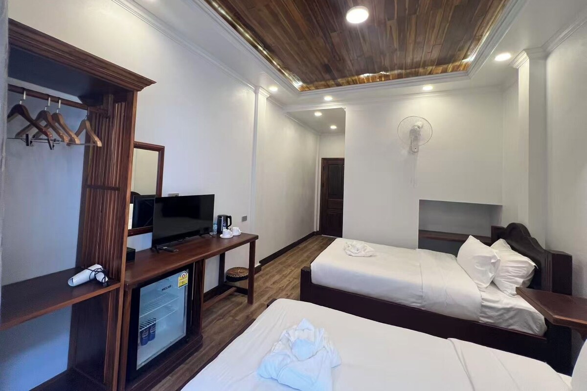 Une chambre d’hôtel avec deux lits, une télévision, un minibar et un plafond en bois.