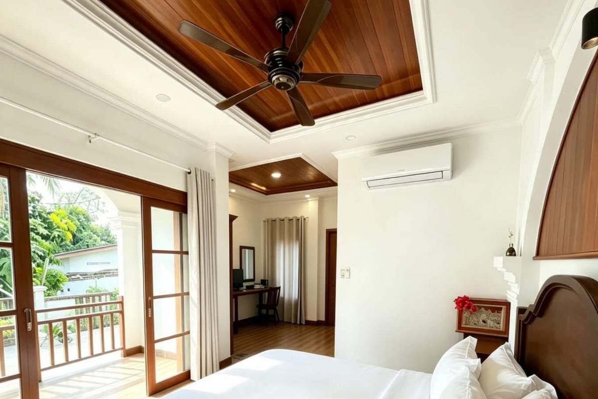 Une chambre d’hôtel équipée d’un lit, d’un ventilateur de plafond, d’un climatiseur, d’un bureau avec une chaise et offrant une vue sur l’extérieur.