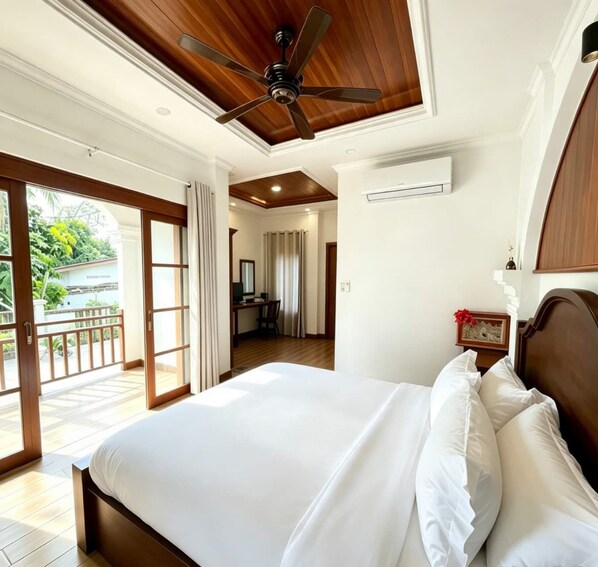 Une chambre d’hôtel équipée d’un lit, d’un ventilateur de plafond, d’un climatiseur, d’un bureau avec une chaise et offrant une vue sur l’extérieur.