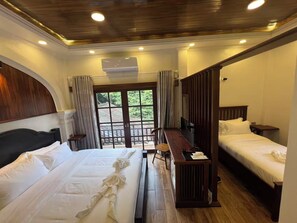 Une chambre d’hôtel avec deux lits, un plafond en bois, une grande fenêtre avec des rideaux et un bureau en bois.
