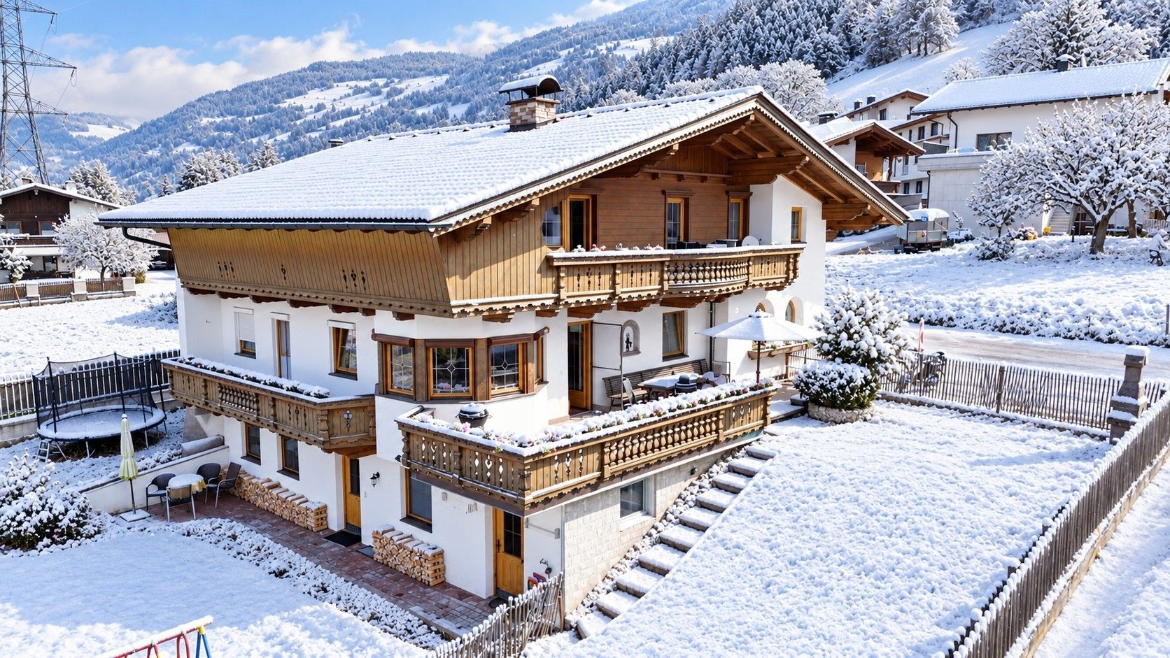 Un chalet à deux étages doté d’un balcon, d’une façade en bois et surplombant un paysage enneigé.