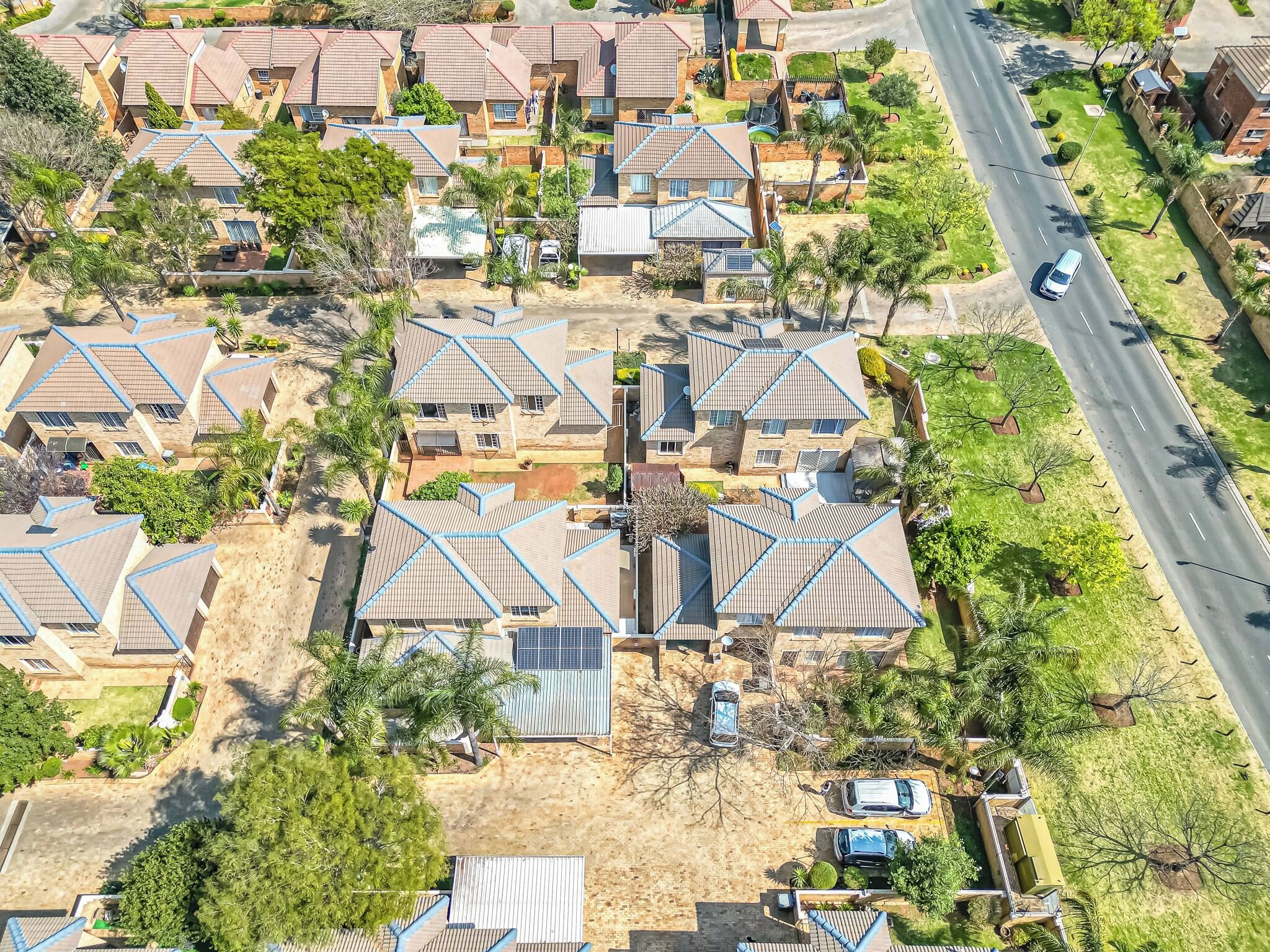 A residential area with multiple houses, a road, and some greenery.