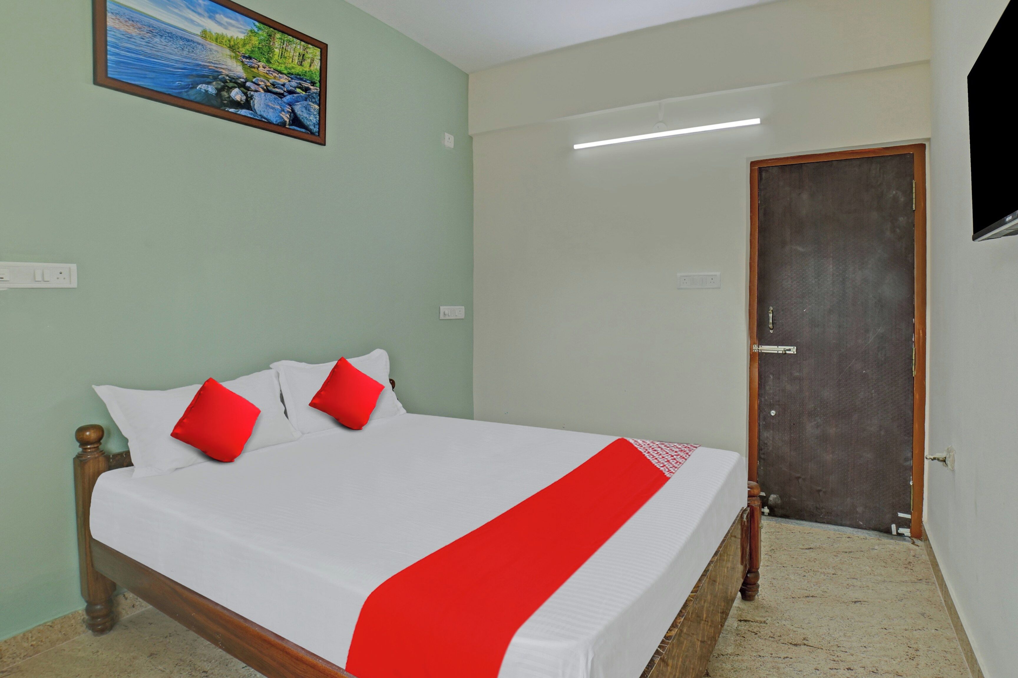 Una habitación de hotel con una cama, una puerta y un cuadro en la pared.