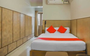 Una habitación de hotel con una cama, un teléfono junto a ella y un equipo de aire acondicionado.