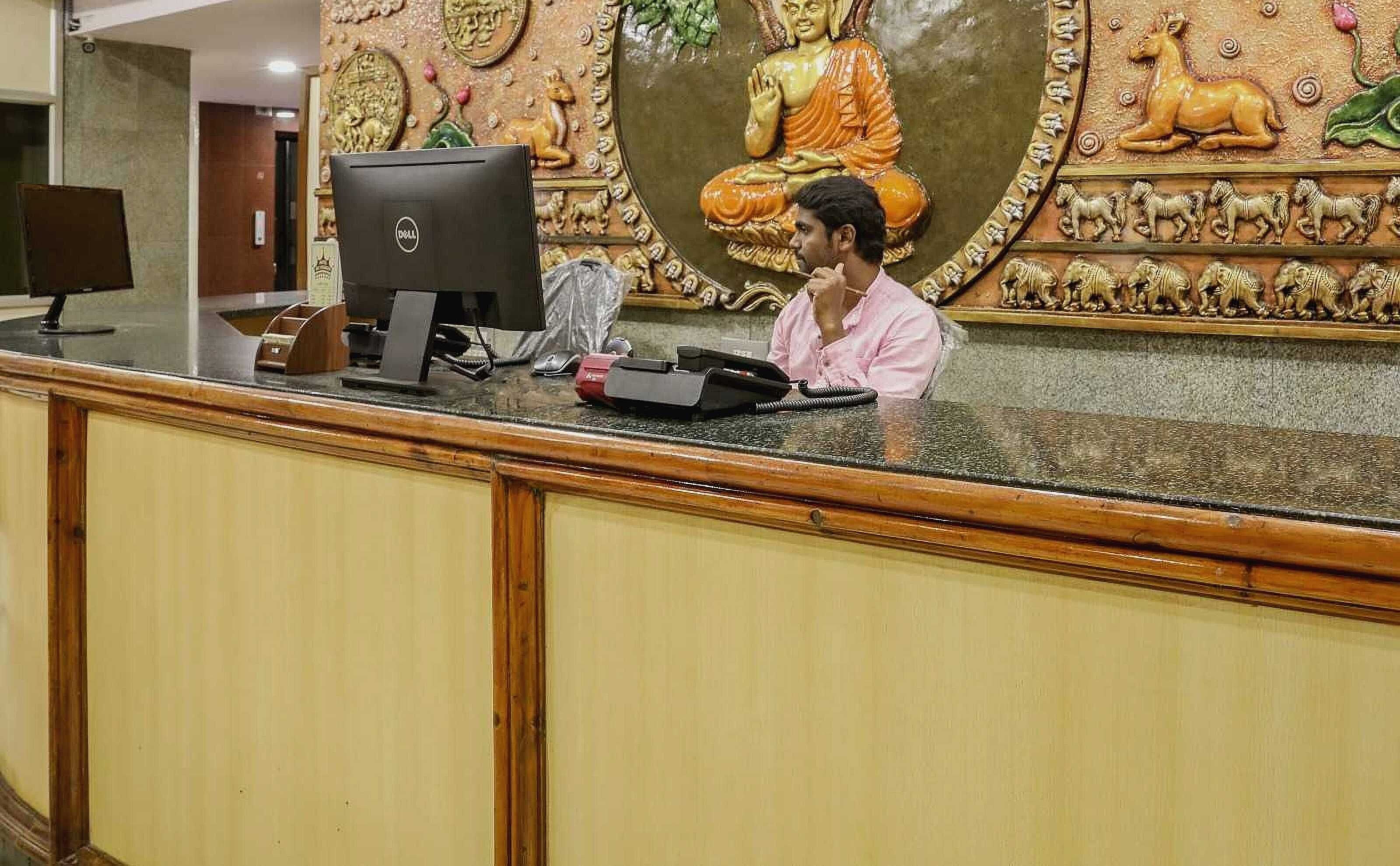 A reception desk with a computer, a phone, and a decorative wall with a seated figure and animals.