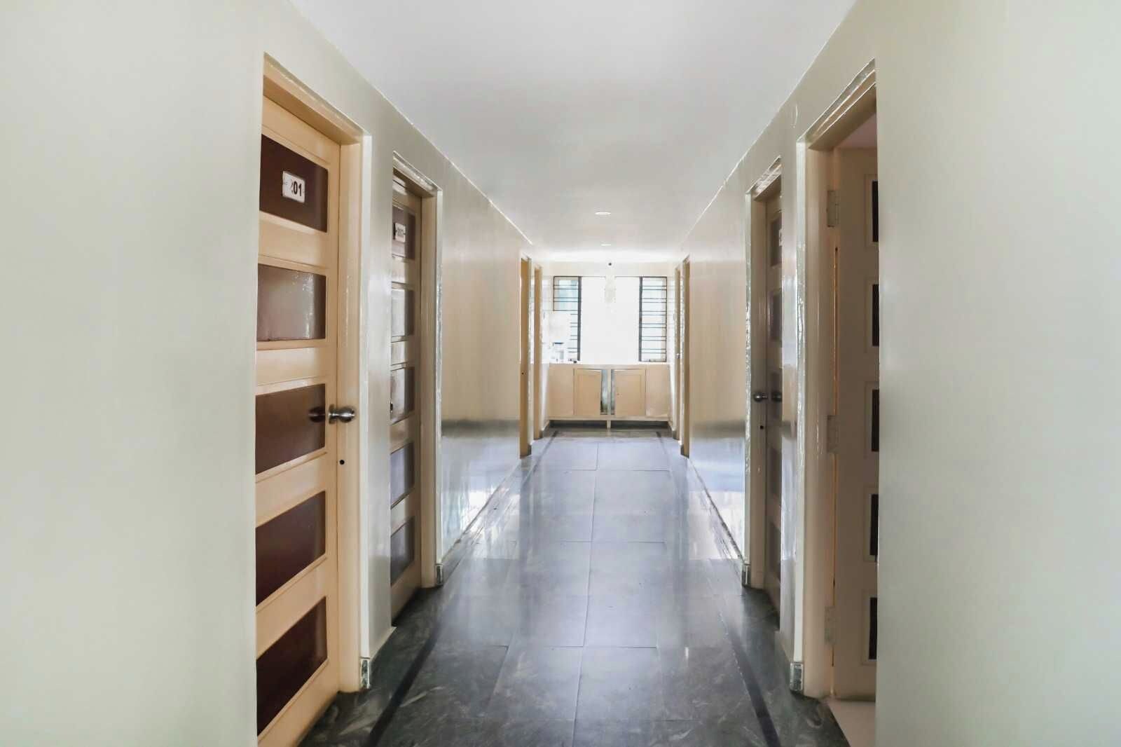 A corridor with doors on both sides, leading to a room with a window.