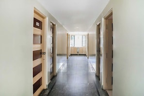 Ein Korridor mit Türen an beiden Seiten, der zu einem Zimmer mit einem Fenster führt.