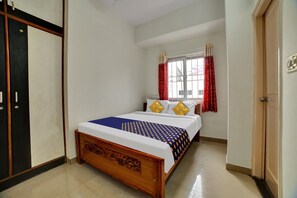 Un dormitorio con cama, una ventana con cortinas y un armario.