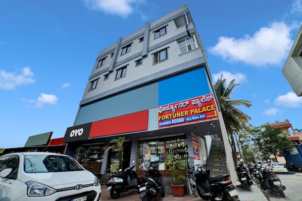 Un edificio de varios pisos con un letrero llamativo que anuncia 'FORTUNER PALACE' y habitaciones disponibles.