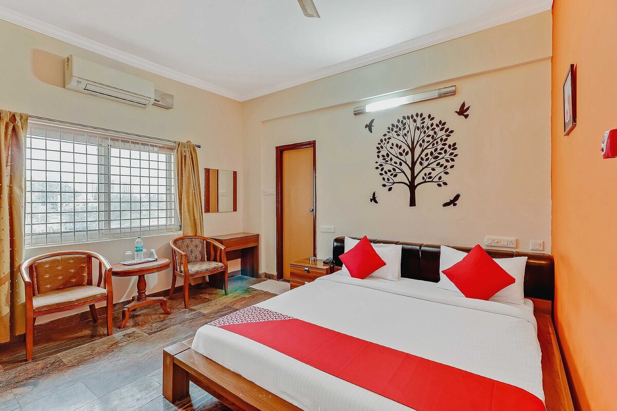 A hotel room with a large bed, a desk, a chair, and a window with curtains.